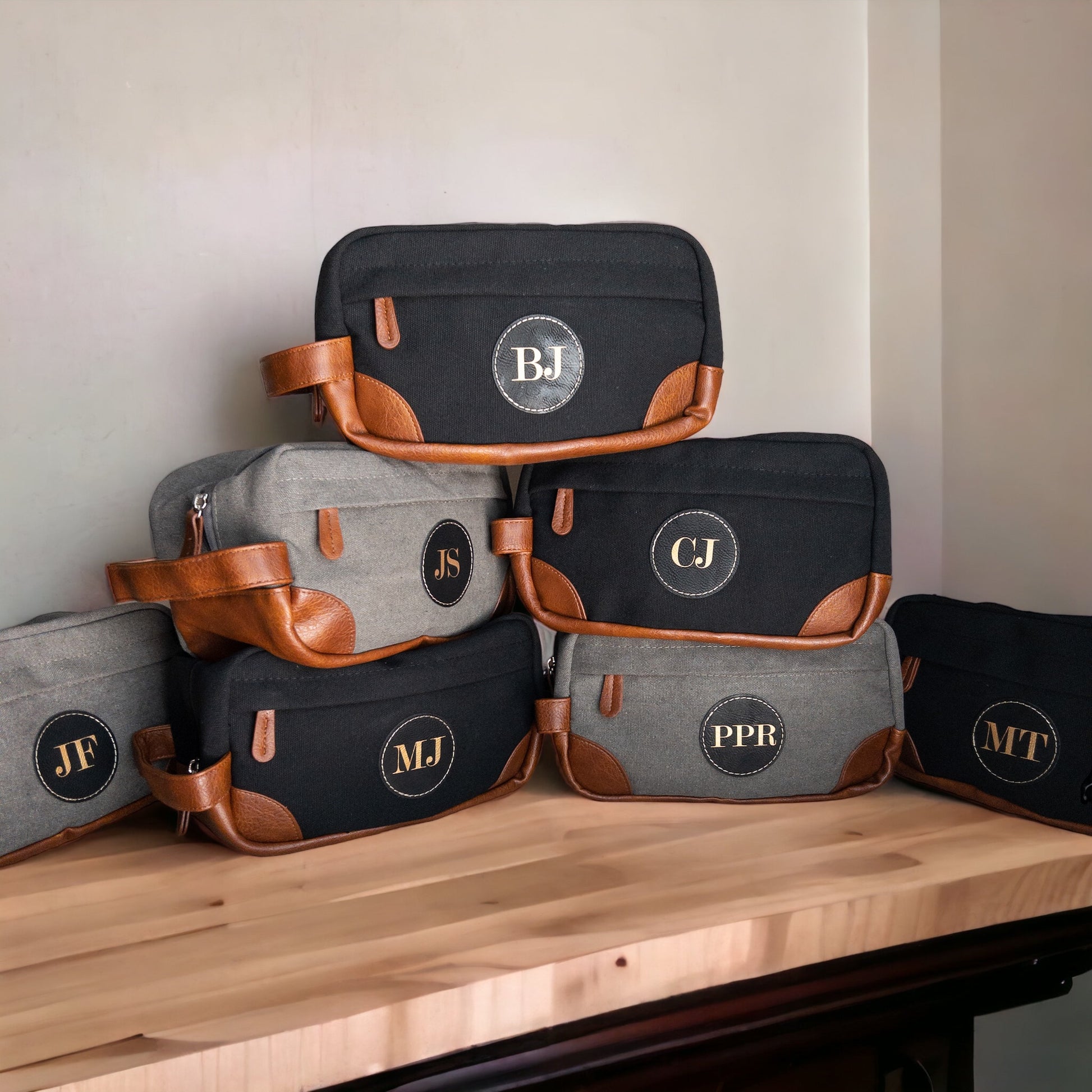 A sleek toiletry bag made of water-resistant canvas, displayed in a hung position, showcasing various compartments and a distinctive customizable leather patch.