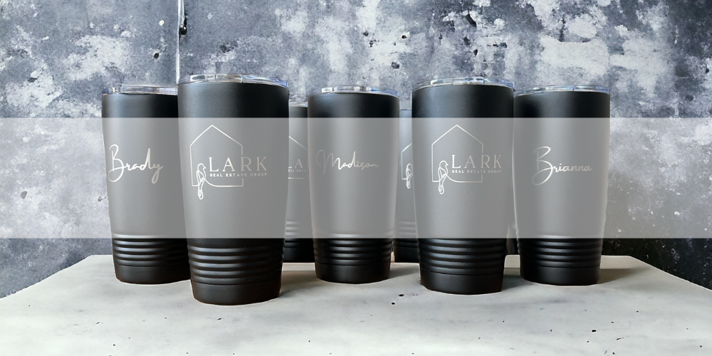 Set of custom engraved black tumblers with personalized names and Lark Real Estate Group logo, designed for corporate wholesale orders and branding.