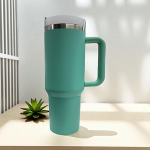 Teal travel mug with a white lid on a light surface with a plant in the background